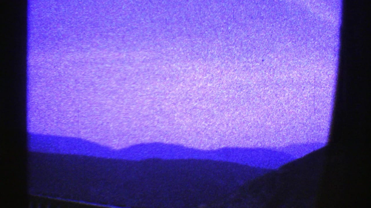 The lower portion of the window view shows dark foreground shapes with distant mountain silhouettes and heavy purple-blue 8mm coloration.