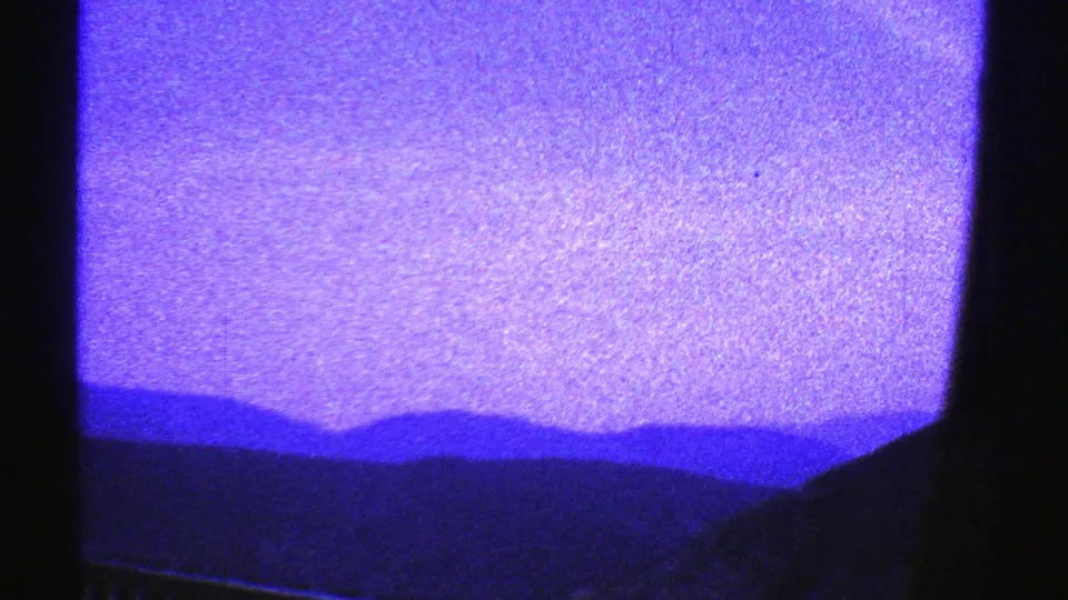 The lower portion of the window view shows dark foreground shapes with distant mountain silhouettes and heavy purple-blue 8mm coloration.