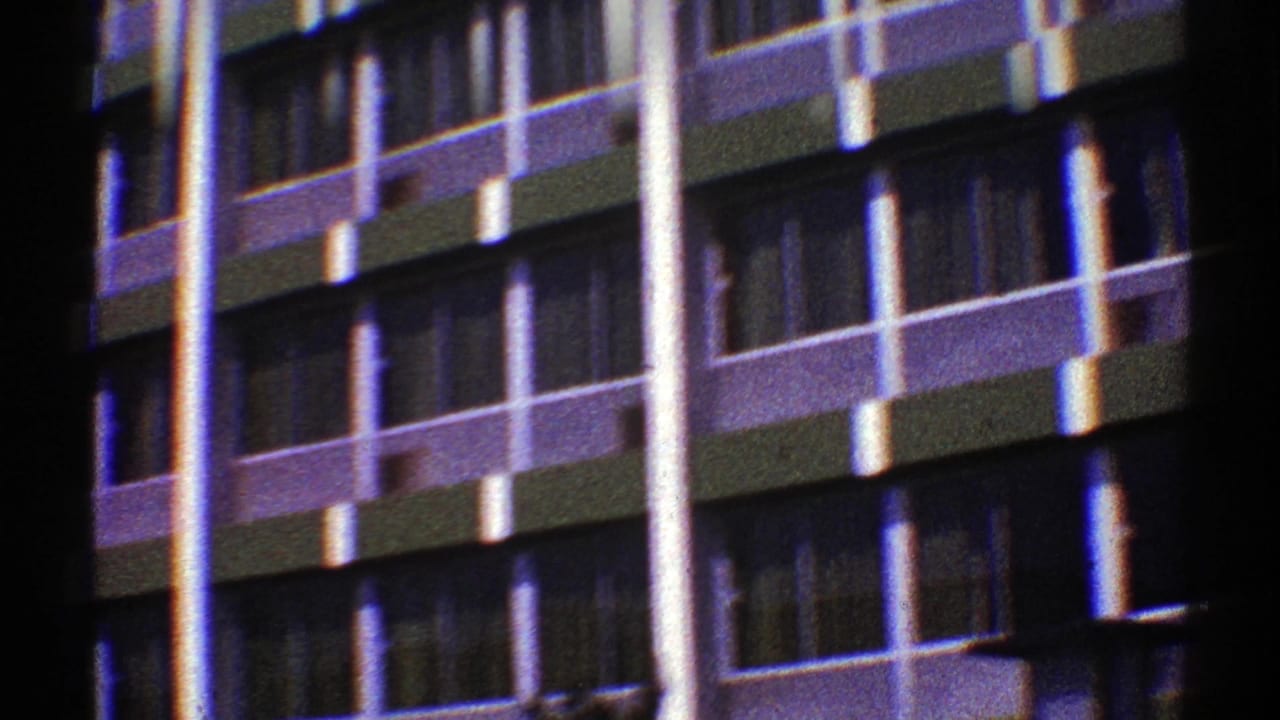 1969 Nevada 8mm frame showing a modernist high-rise exterior with repeating windows, balconies, and bright vertical columns.