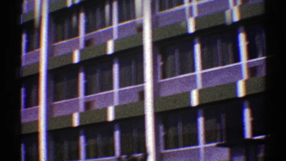 1969 Nevada 8mm frame showing a modernist high-rise exterior with repeating windows, balconies, and bright vertical columns.