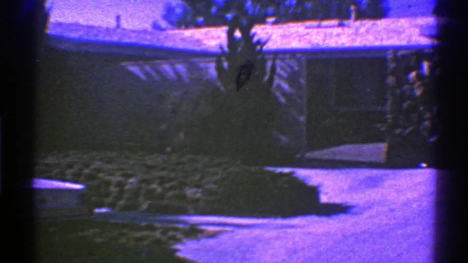 1969 Nevada 8mm frame with a suburban house, driveway, roofline, and shrubs softened by exposure and film-frame shadows.