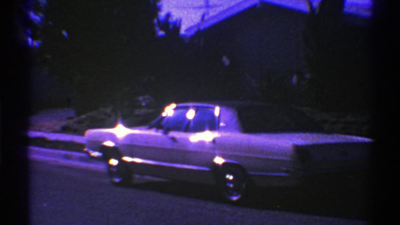 Classic sedan seen in profile on a residential street at night.
