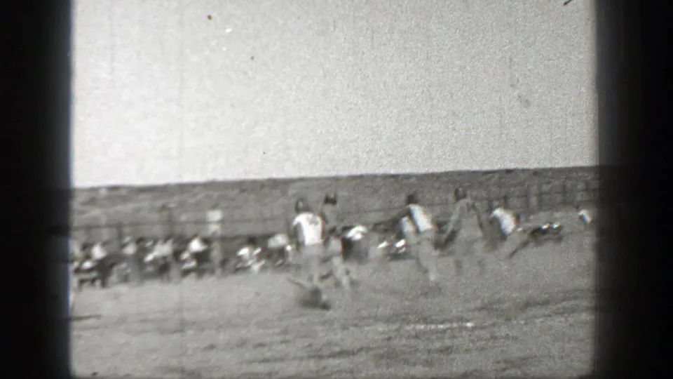 A Washington 1938 football play moves across the frame, with several players running and sideline figures beyond the action.