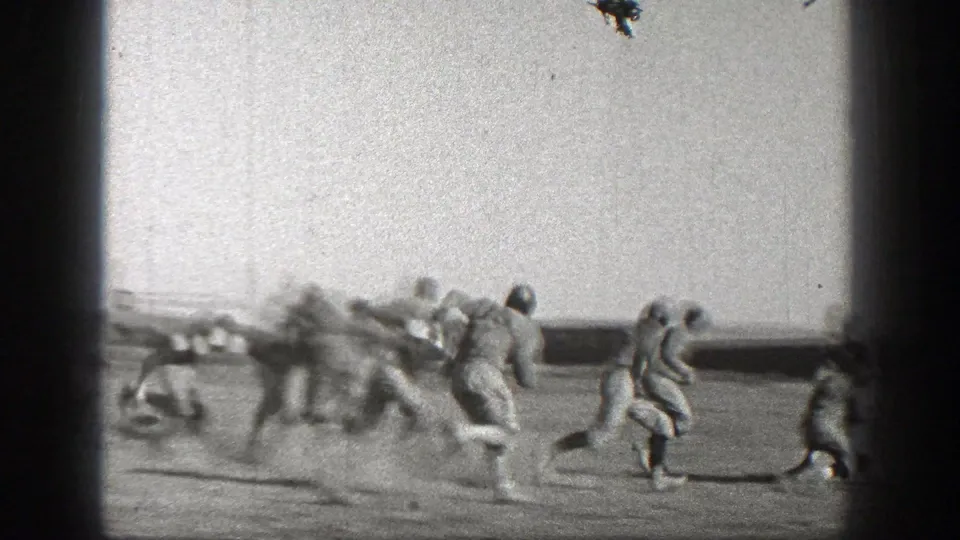 Washington 1938 football action with several uniformed players running in a loose pack across the dusty field.
