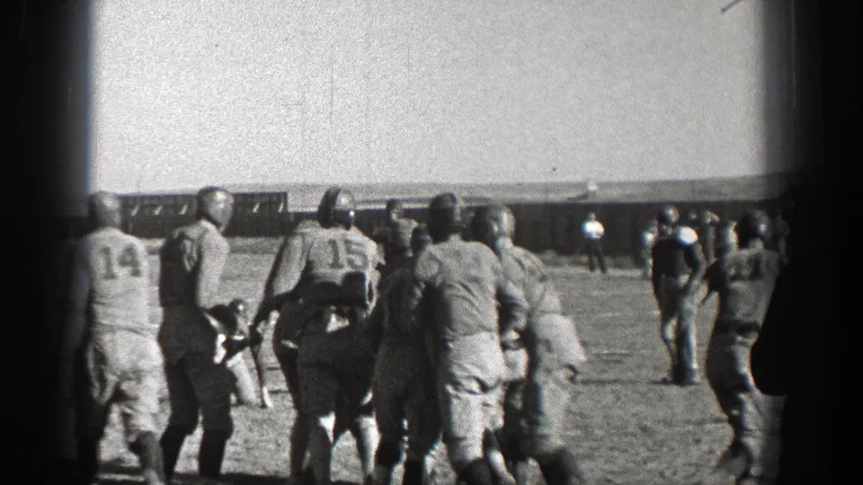 Washington 1938 football scene with numbered players and sideline figures watching the field before the next play.