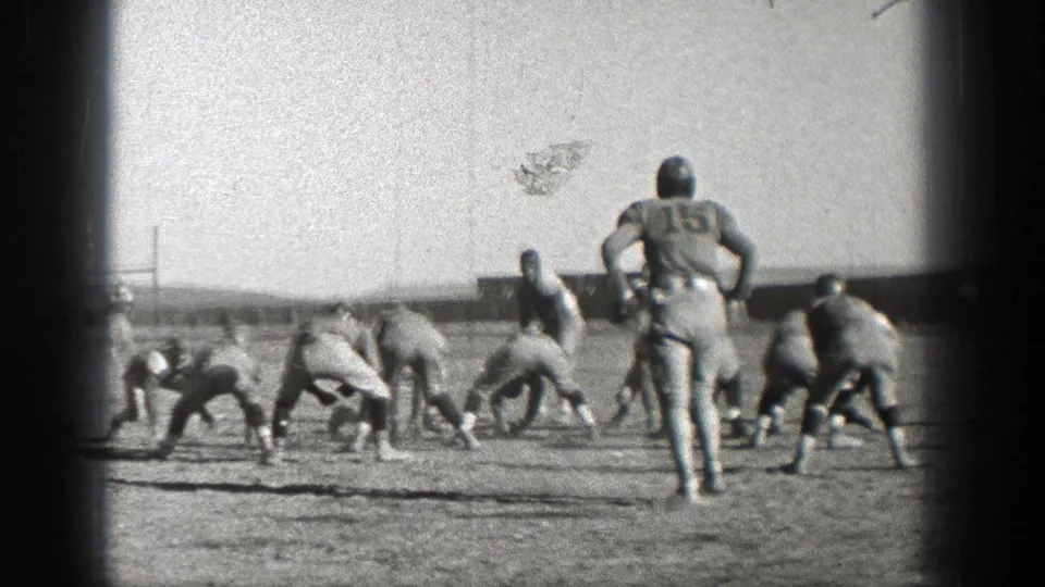 Washington 1938 home-movie frame showing football players crouched at the line with a numbered player standing behind them.