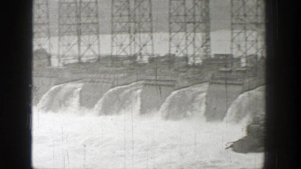 Washington 1938 home-movie frame showing dam spillways and white water beneath the bridge structure.