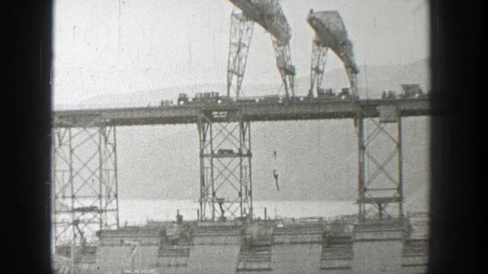 1938 Washington 8mm still of bridge construction, showing cranes on the deck and a hanging hook over the water.