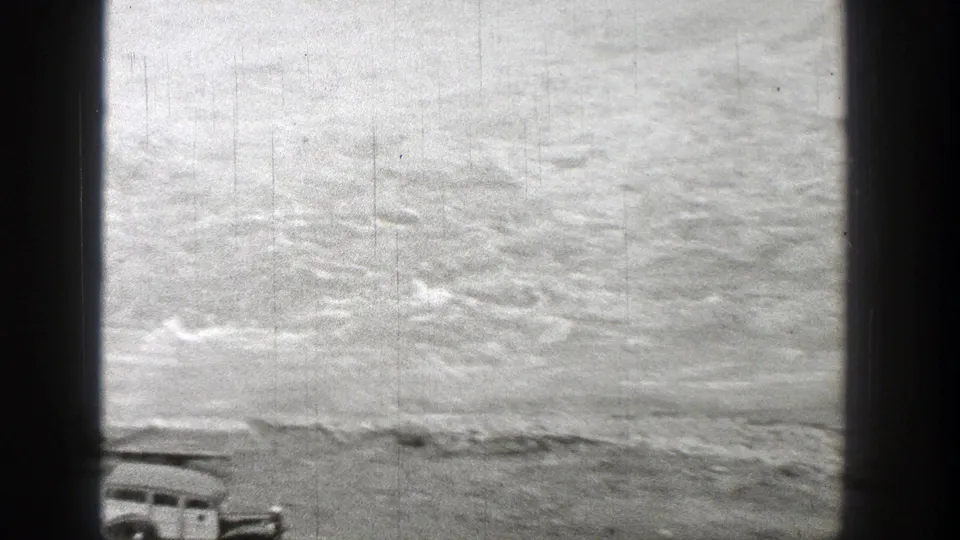 A brief 1938 Washington home-movie frame turns toward rippling water, with the top of a car partly visible at the lower edge.