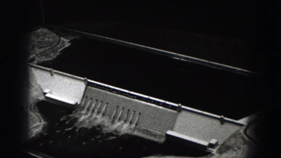 1938 Washington 8mm frame showing a concrete spillway-like structure, railings, dark water, and rough banks.