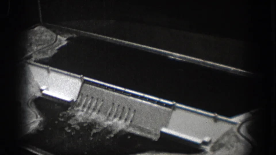 1938 Washington 8mm frame showing an overhead view of a spillway-like concrete structure beside dark water and rough ground.