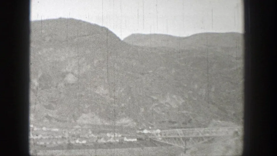 Distant Washington landscape with low buildings under bare hills and a possible bridge or trestle visible near the right edge.