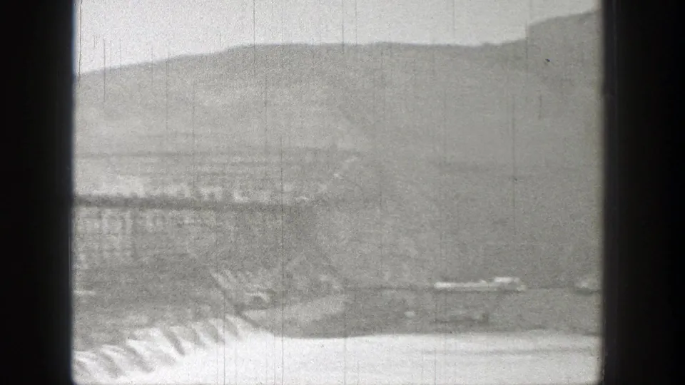 Soft 1938 Washington 8mm frame of bridge structure and water below, partially obscured by dark frame edges and haze.