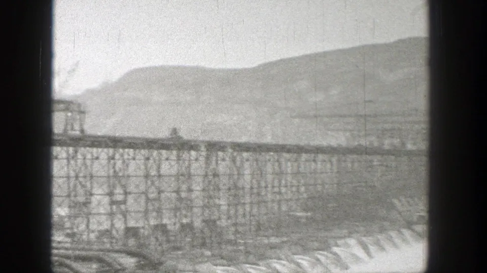 1938 Washington 8mm frame showing spillway water beneath steel supports and a partially framed dam structure.
