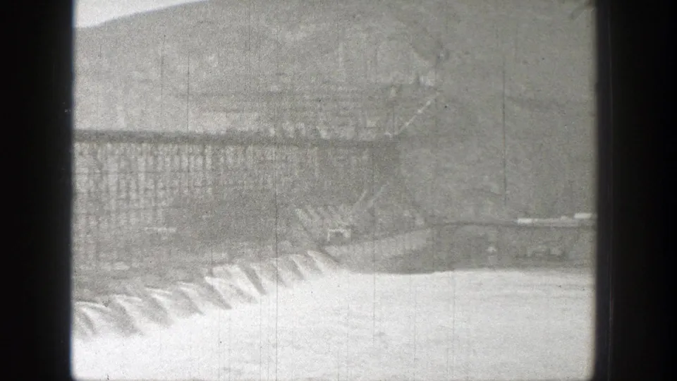 Washington 1938 frame with industrial construction over water, dark scan borders, and a hillside beyond the works.