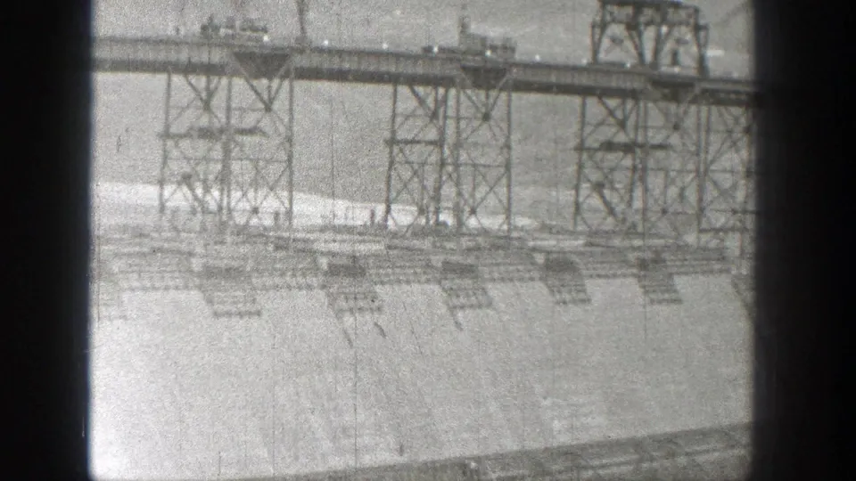1938 Washington archival frame with metal trusswork, tall supports, and pale barren ground below.