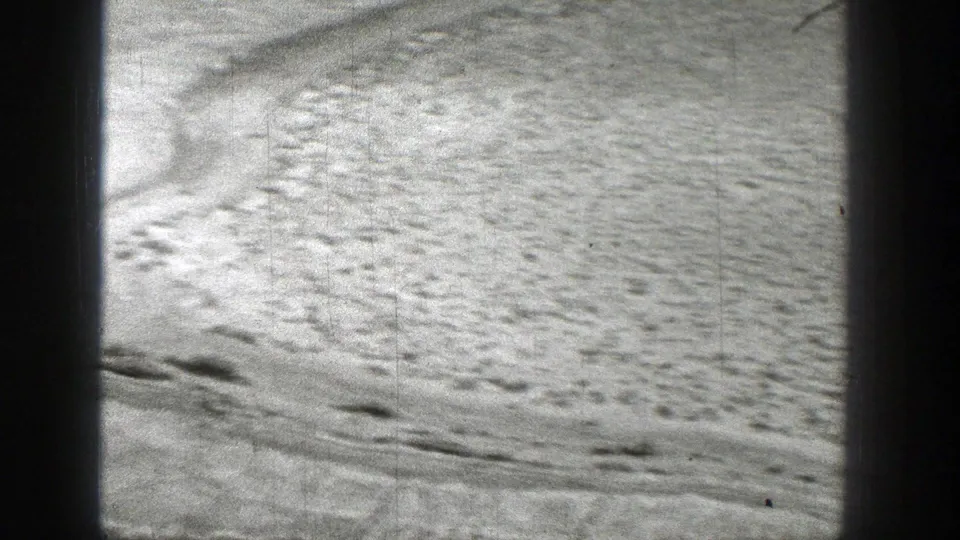 1938 Washington 8mm frame showing textured dry riverbed ground with scattered marks and dark vertical frame-edge obstructions.