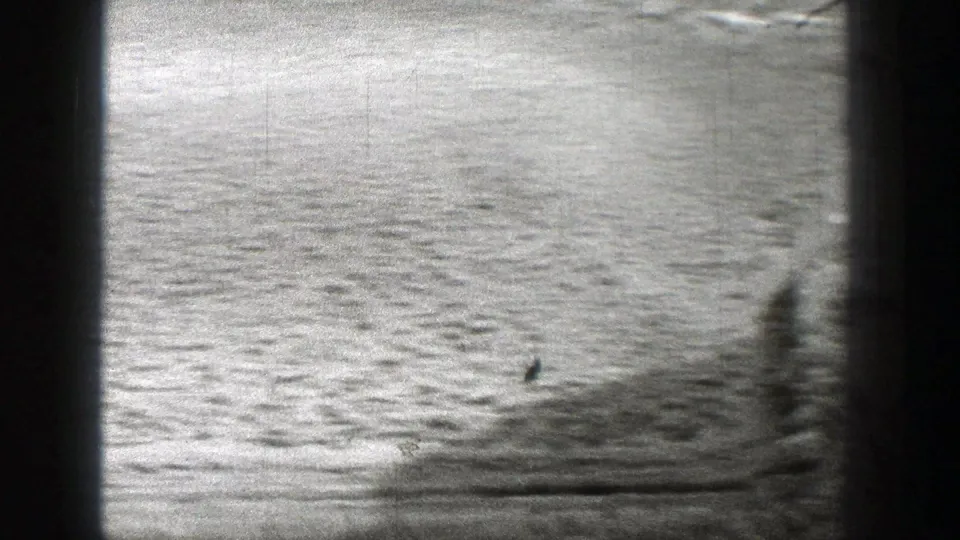Black-and-white 8mm view of a barren Washington riverbed area with shallow surface texture and a dark edge obstruction.