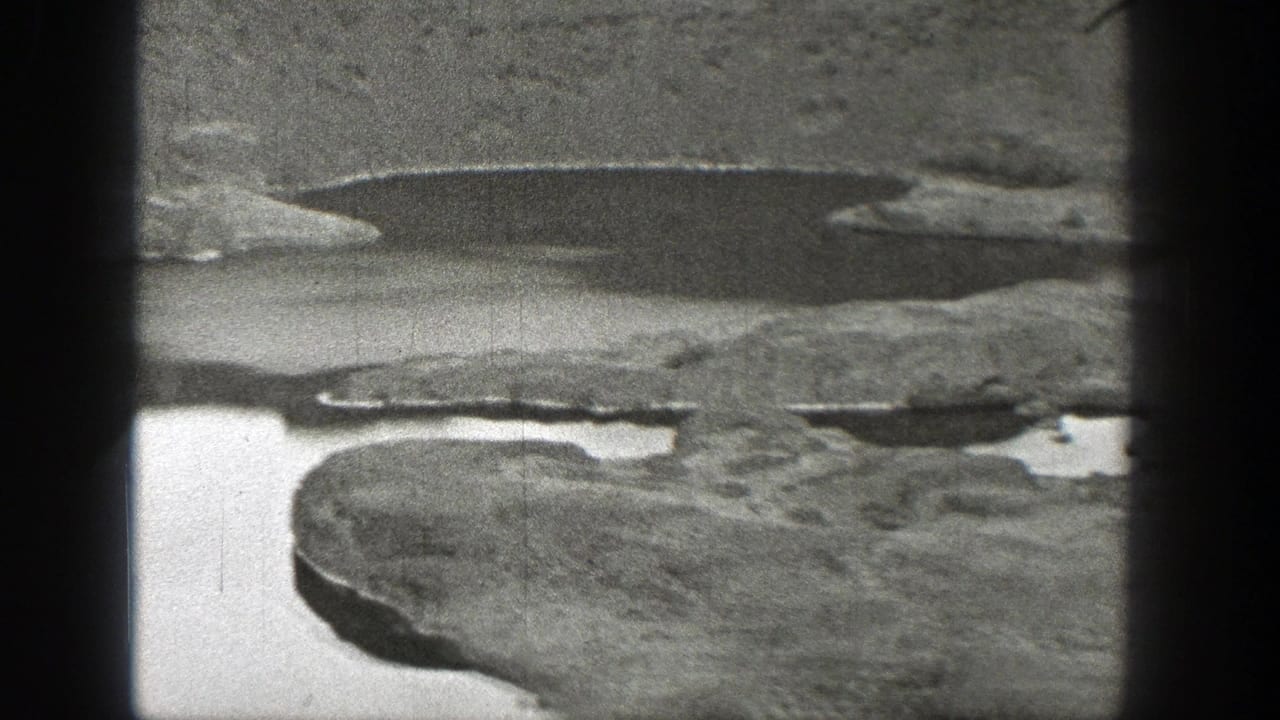 Rocky landscape with scattered water pools seen through dark film-frame edges.