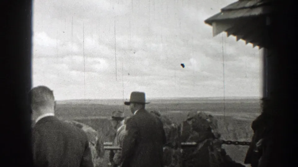 Men in 1930s dress stand on a Washington viewing platform, looking out over a broad landscape.