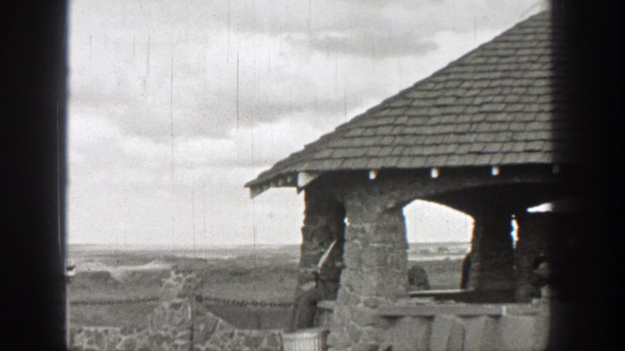 Stone covered picnic shelter overlooking an open landscape under cloudy sky.