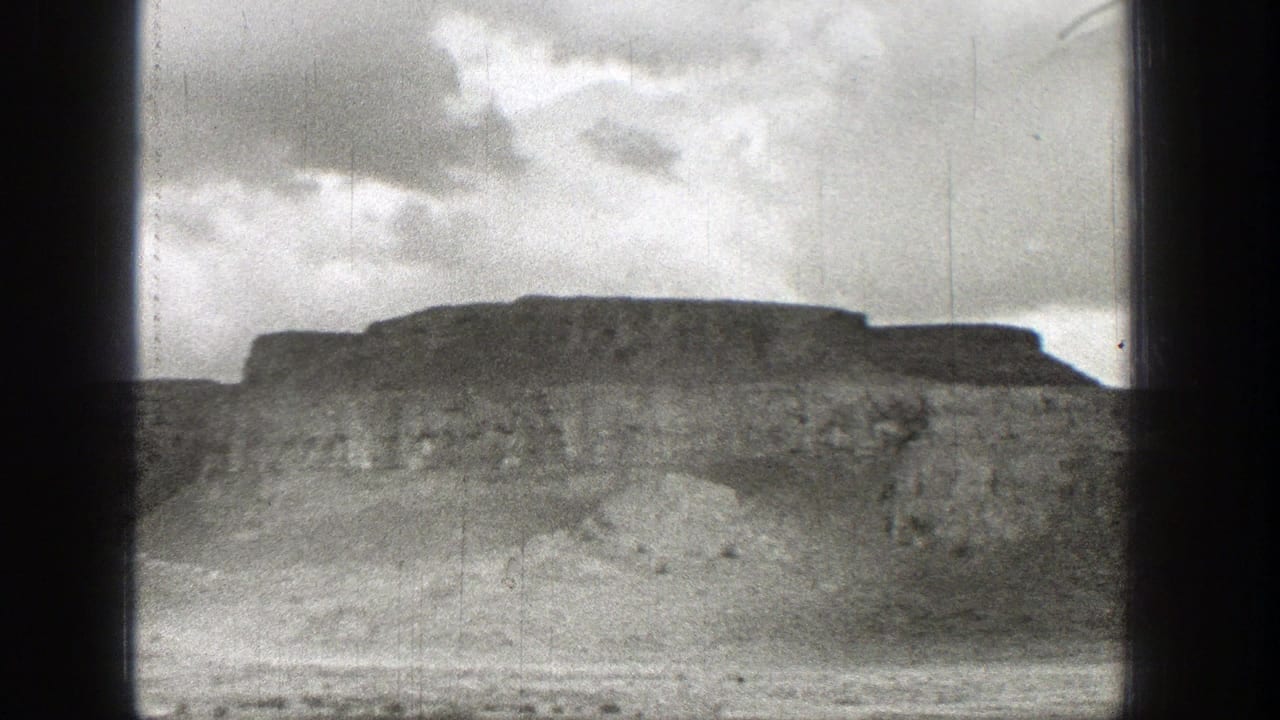 Broad mesa-like ridge beneath clouds with dry ground in the foreground.