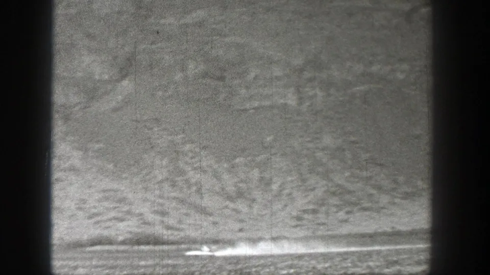 1938 Washington 8mm frame with the small craft or aircraft near lower center-right, its smoke trail spreading over the flat landscape.