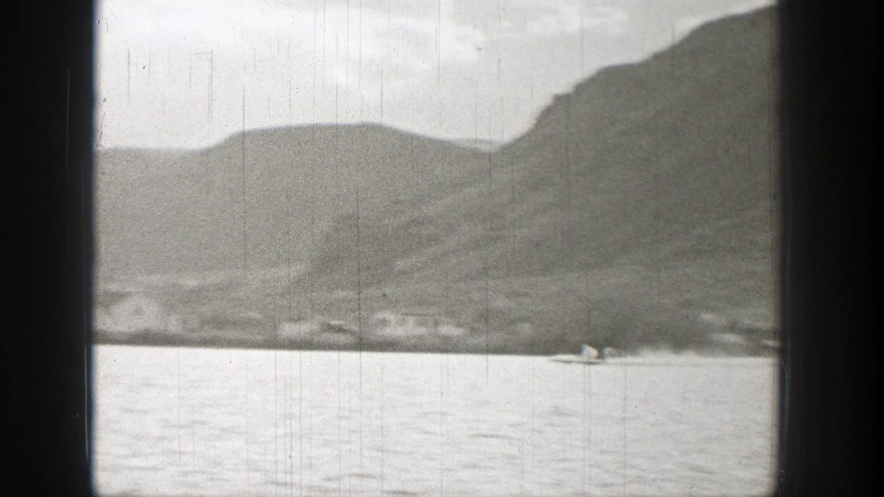 Small boat crossing calm water with hills and shoreline in the distance.