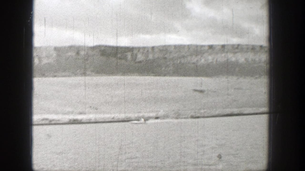1938 Washington 8mm frame showing a small boat moving across a broad river below rugged hills.