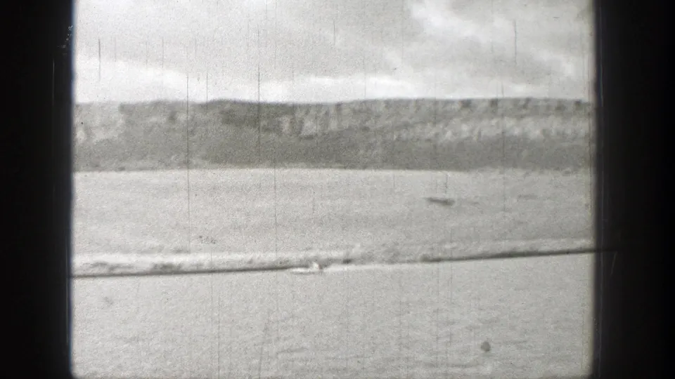 1938 Washington 8mm frame showing a small boat moving across a broad river below rugged hills.