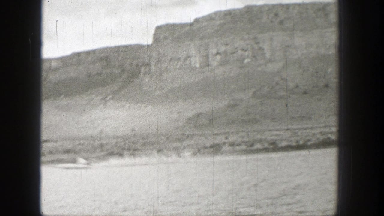 Distant lake and rocky cliffs seen through dark 8mm frame edges.