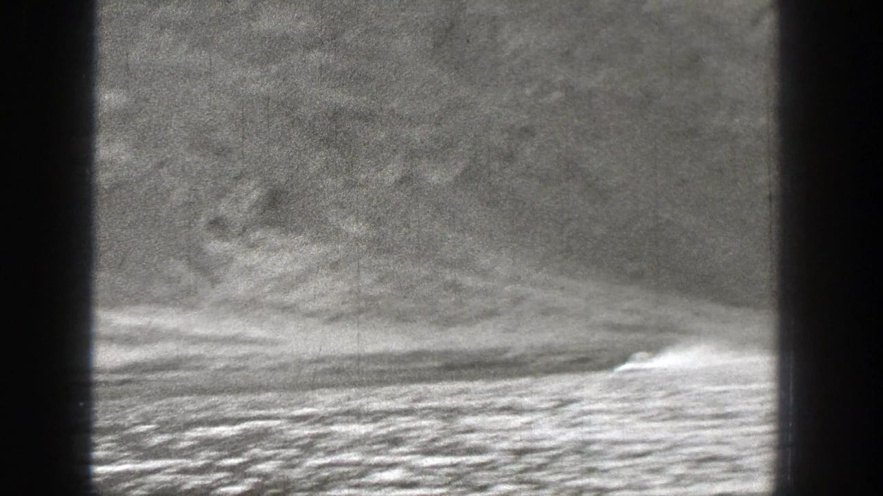 Motorboat speeding near a mountain shoreline with a bright wake.