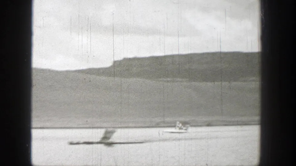 The small watercraft creates a visible wake on the river, with the Washington hillside and shoreline behind it.