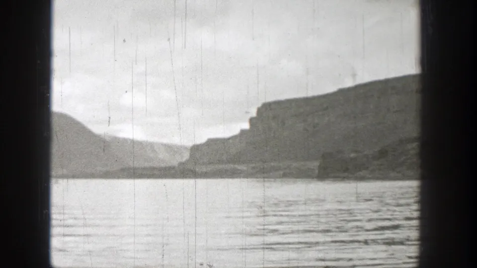 Black-and-white 8mm frame from Washington in 1938 showing rippled lake water and layered mountain forms.