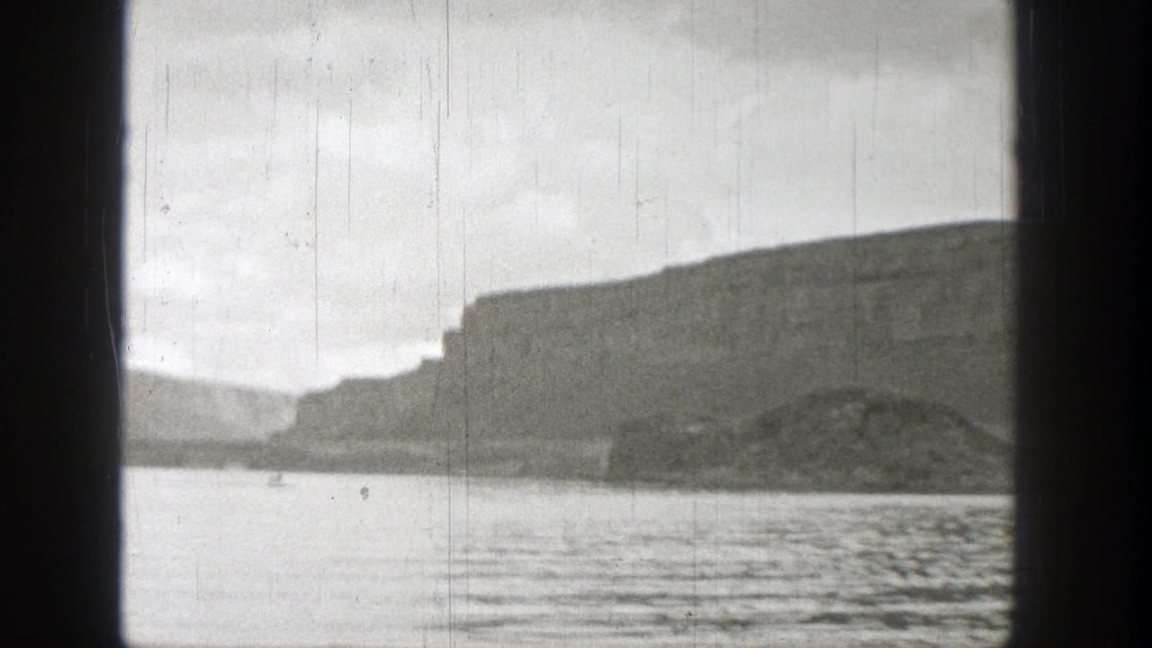 Rippled water in front of distant flat-topped cliffs under a pale sky.