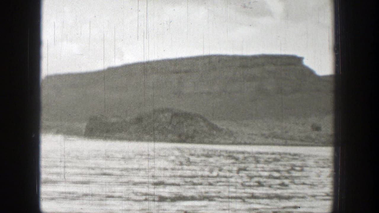 Broad water surface with a distant bluff and low rocky shoreline.