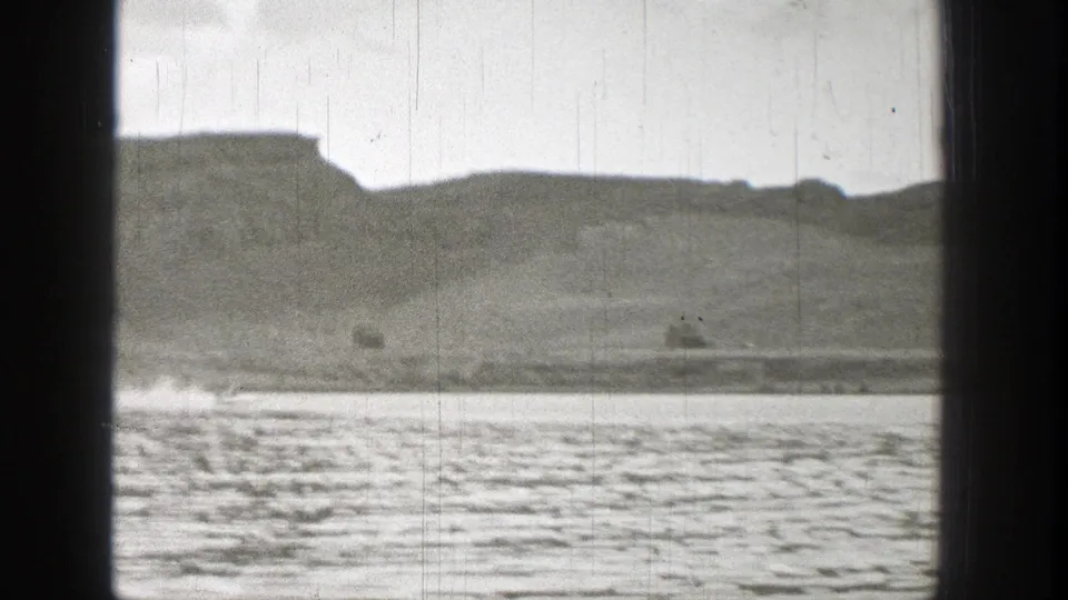 1938 Washington 8mm frame showing low hills, a shoreline edge, and rippled water in a grainy home-movie view.