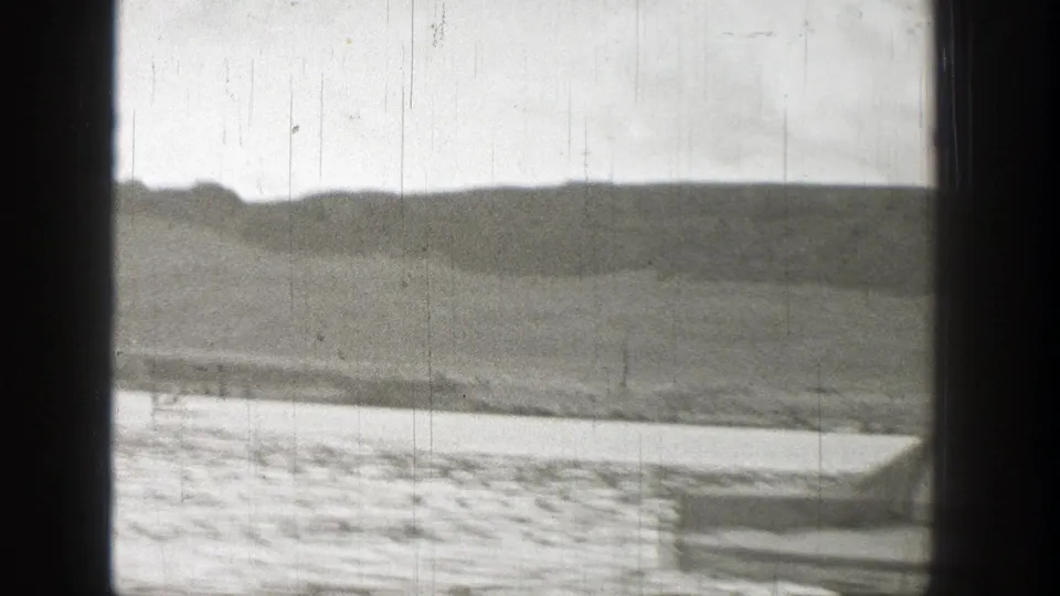 1938 Washington 8mm frame showing distant hills and shoreline across water, with a small foreground edge at the lower right.