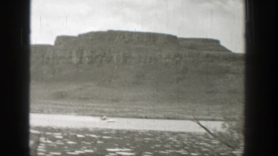 Black-and-white 8mm view in Washington, 1938, with window bars cutting across water and a broad rocky hillside.