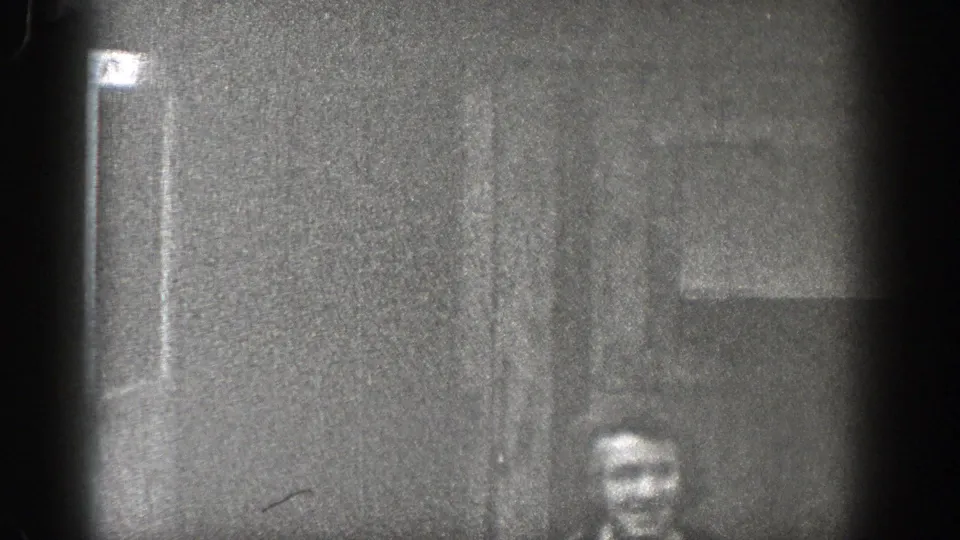 1938 Washington 8mm frame showing a woman partly visible near a dark wall or doorway, with heavy grain and vignetted film edges.