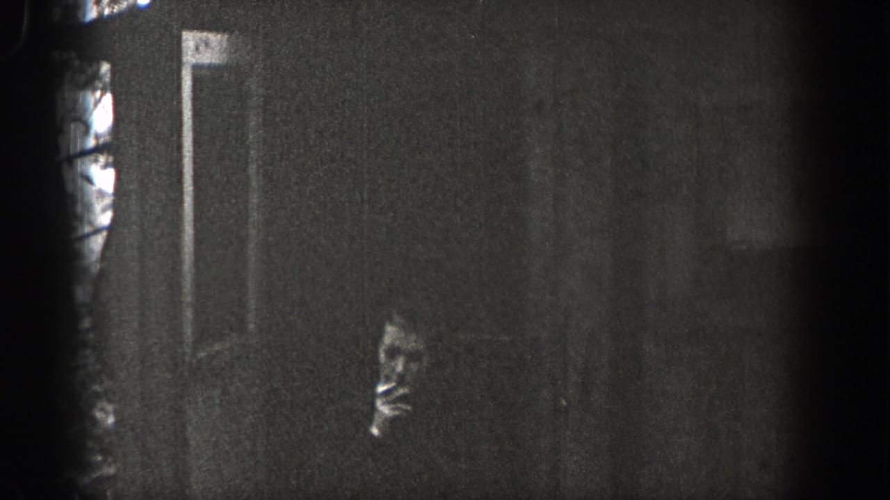 1938 Washington 8mm frame showing a woman in profile near a dark wall or doorway, possibly holding a cigarette, with visible grain.