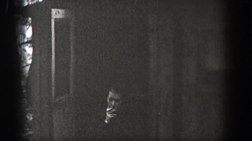 1938 Washington 8mm frame showing a woman in profile near a dark wall or doorway, possibly holding a cigarette, with visible grain.
