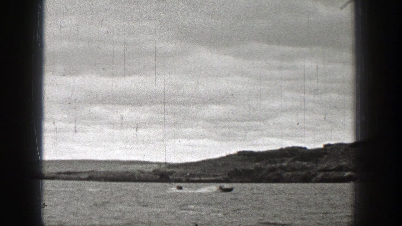 Small boats on water beyond a dark vessel window frame and distant shoreline.