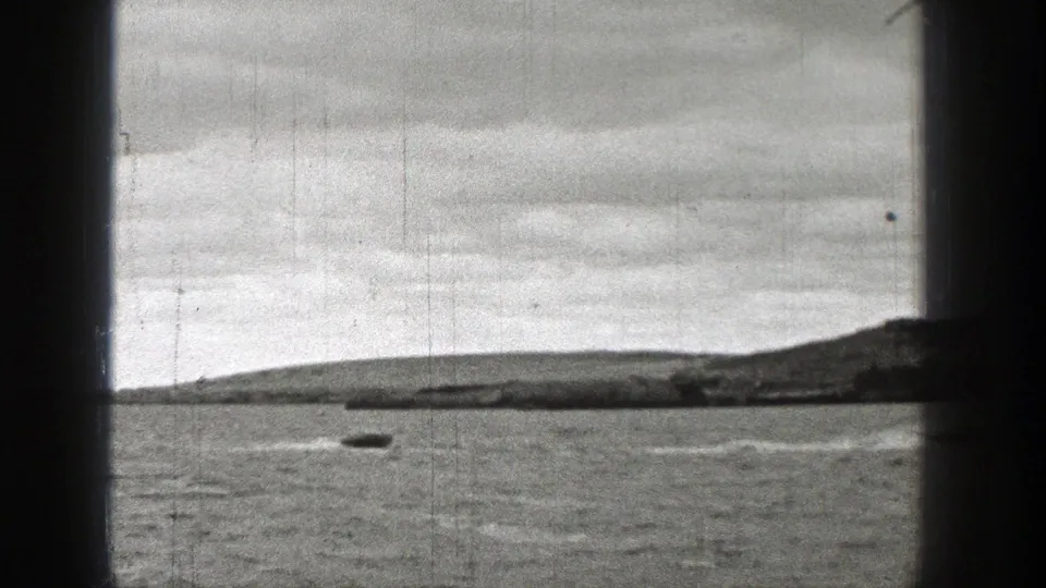 1938 Washington home-movie frame showing one visible motorboat on open lake water, with a distant shoreline, cloudy sky, and dark frame edges.