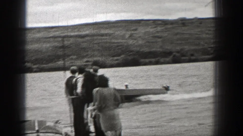 Washington shoreline spectators watch a small boat pass in this 1938 8mm home-movie frame.