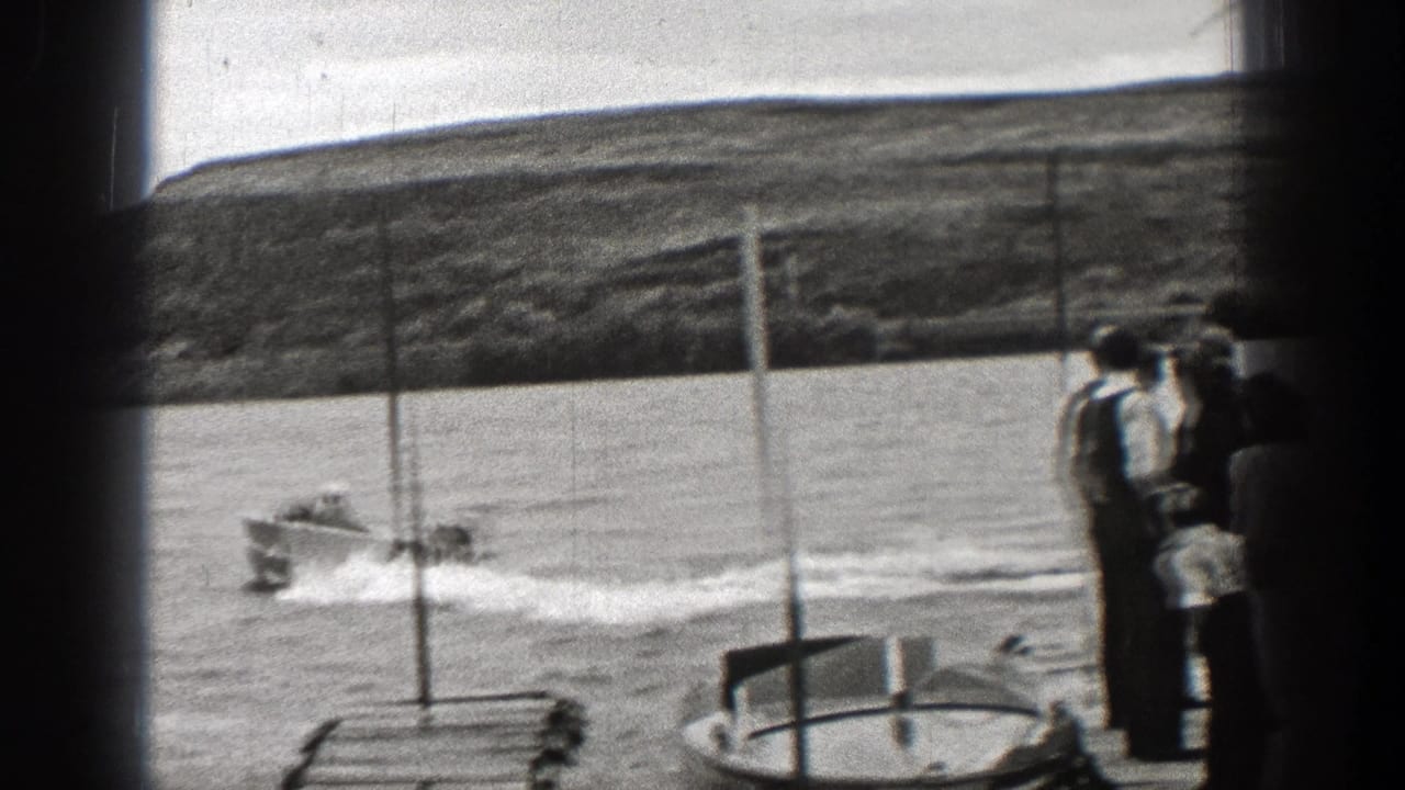 A small motorboat leaves a curved wake as Washington spectators watch from shore in 1938 home-movie footage.