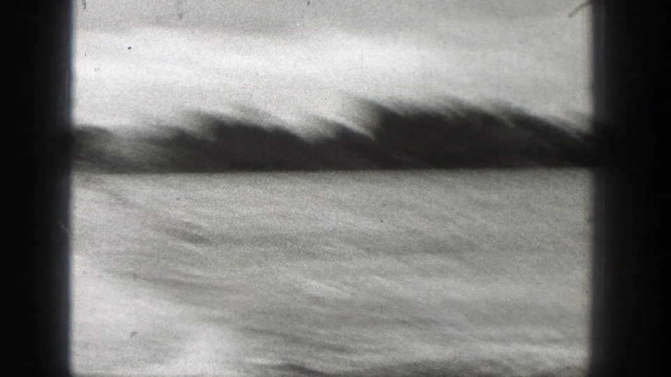 Soft 1938 Washington 8mm frame of rippled water and a blurred shoreline, with strong dark gate borders and film texture.