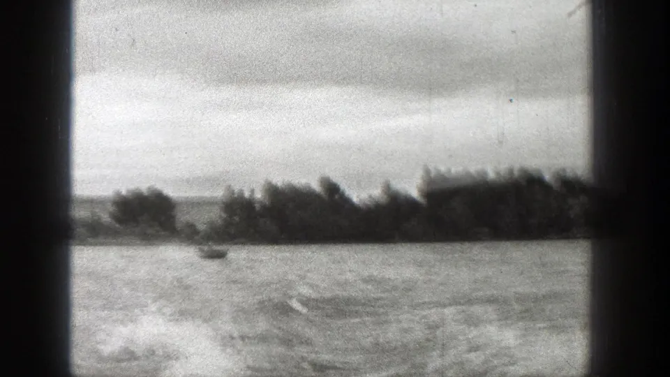1938 Washington 8mm frame showing a small boat crossing open water near a distant wooded shoreline.