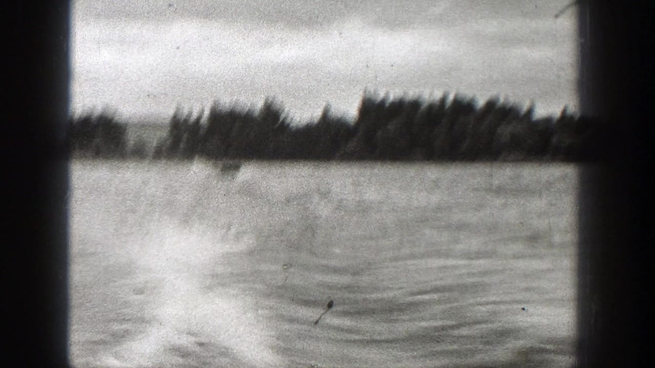 Black-and-white 8mm view of open water, wake patterns, and a wooded shore in Washington, 1938.