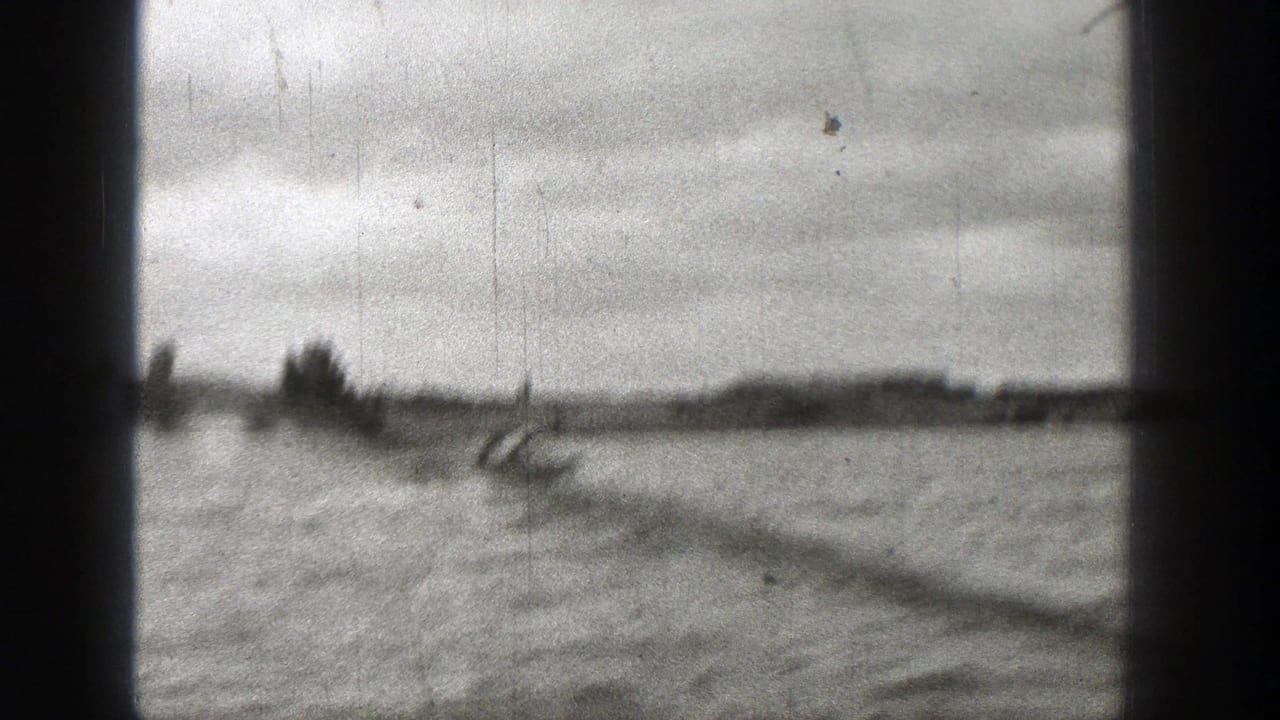 Small motorboat crossing choppy water beyond dark film-frame borders.